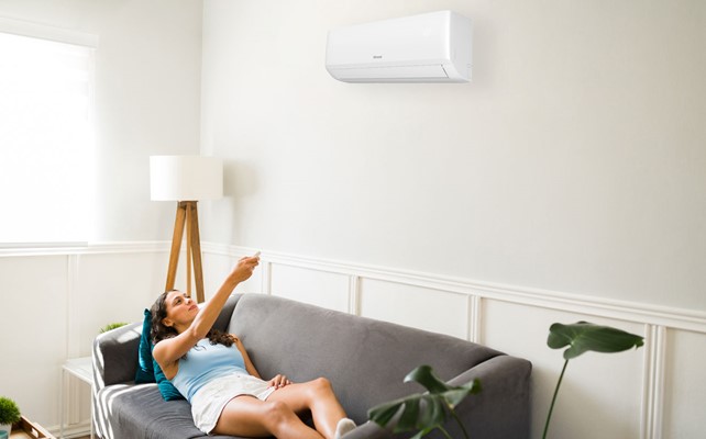 man lies on couch below heat pump - Stay cool with an air conditioner from Rinnai