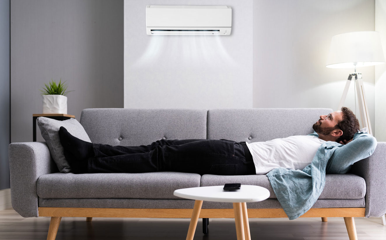 man lies on couch below heat pump - Stay cool with an air conditioner from Rinnai